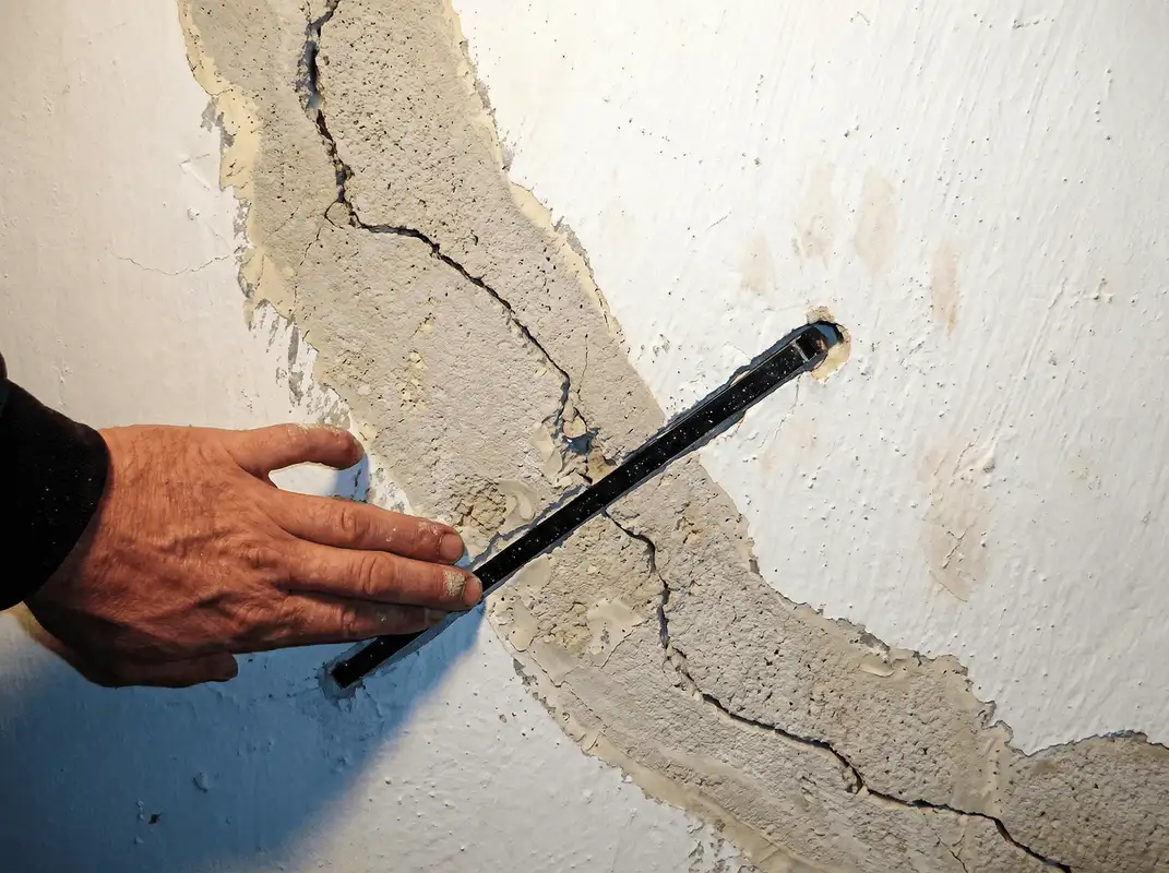 A wall with a large crack is being inspected by a professional in Savannah, GA
